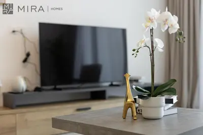 a living room with a tv and a table with flowers at Mira Holiday Homes - Luxury and cosy 1 bedroom in JVC in Dubai