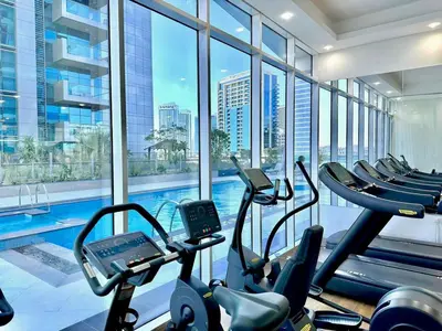 a gym with a swimming pool and cardio machines at Prime Location , Bright Studio , High Floor in Dubai