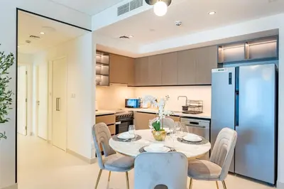 a kitchen with a table and chairs and a refrigerator at 2 Br in in Burj Crown by Pk Holidays in Dubai