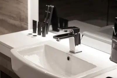 a white bathroom sink with a black faucet at Luxurious New Studio! 2 Double Beds! Sleek Design & High-End Amenities in Dubai Downtown in Dubai