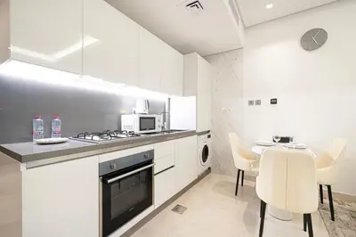a kitchen with white cabinets and a table and chairs at Luxurious New Studio! 2 Double Beds! Sleek Design & High-End Amenities in Dubai Downtown in Dubai