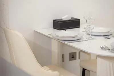 a white table with white plates and a black box at Luxurious New Studio! 2 Double Beds! Sleek Design & High-End Amenities in Dubai Downtown in Dubai