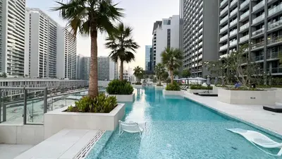 a large swimming pool with palm trees and buildings at Luxurious New Studio! 2 Double Beds! Sleek Design & High-End Amenities in Dubai Downtown in Dubai