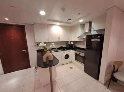 a kitchen with a table with a vase of flowers on it at Spacious 1BR unit with Lake View in Dubai