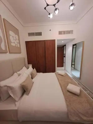 a large white bed in a room with a mirror at Spacious 1BR unit with Lake View in Dubai