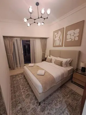 a bedroom with a large bed and a chandelier at Spacious 1BR unit with Lake View in Dubai