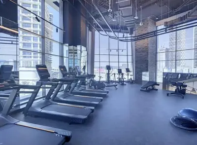 a gym with rows of exercise equipment and large windows at Burj Khalifa & Lagoon View , Private 1 Bedroom in Dubai