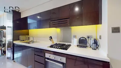 a kitchen with wooden cabinets and a stove top oven at Modern Studio in Majestine in Dubai