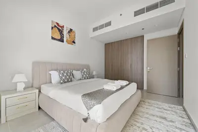 a bedroom with a large white bed and a night stand at Luxury 1BR apartment at Creek Edge Tower 2 in Dubai