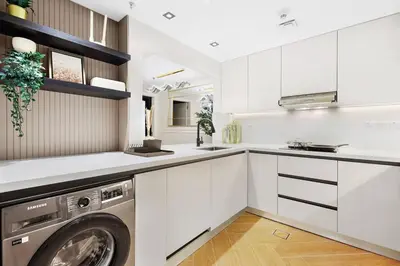 a white kitchen with a washing machine in it at Burj Khalifa View 2BR Steps from Dubai Mall & Metro in Dubai