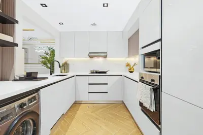 a kitchen with white cabinets and a washer and dryer at Burj Khalifa View 2BR Steps from Dubai Mall & Metro in Dubai