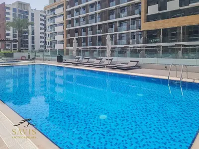 a large swimming pool with chairs in front of a building at Savis Homes - Azizi Riviera 43 - Chic Studio Near Downtown and Business Bay in Dubai
