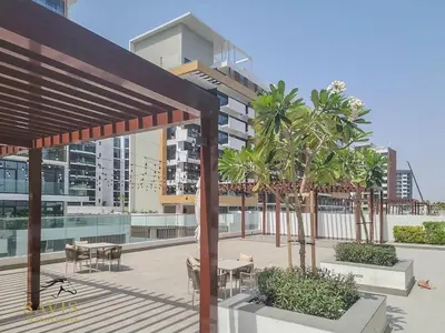 a patio with tables and palm trees in front of a building at Savis Homes - Azizi Riviera 43 - Chic Studio Near Downtown and Business Bay in Dubai