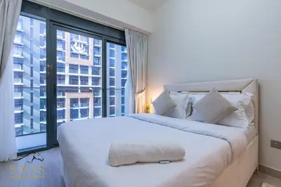 a bedroom with a large bed with a large window at Savis Homes - Azizi Riviera 43 - Chic Studio Near Downtown and Business Bay in Dubai