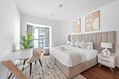 a white bedroom with a large bed and a desk at Cozy 1-Bedroom Apartment In Princess Tower in Dubai