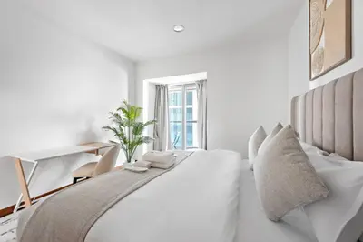 a white bedroom with a white bed and a desk at Cozy 1-Bedroom Apartment In Princess Tower in Dubai