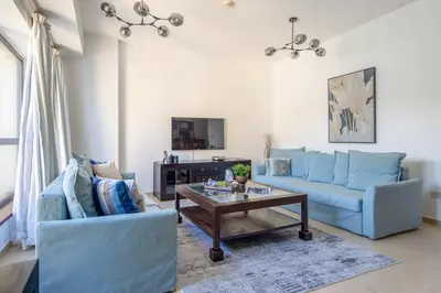 a living room with two blue couches and a coffee table at Frank Porter - Shams 4 in Dubai