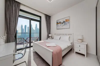 a white bedroom with a bed and a large window at Marina Vista Private Beach 2BR in Dubai