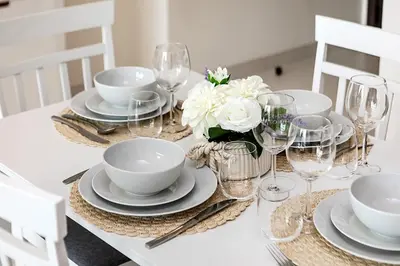 a white table with plates and glasses and flowers on it at Marina Vista Private Beach 2BR in Dubai