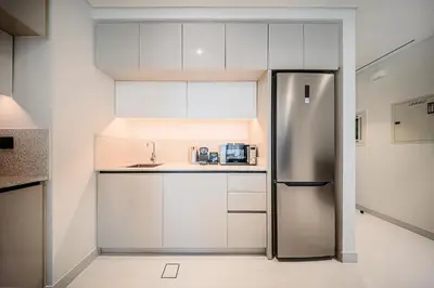 a kitchen with white cabinets and a stainless steel refrigerator at Stunning 1 bedroom sea view apartment in Dubai