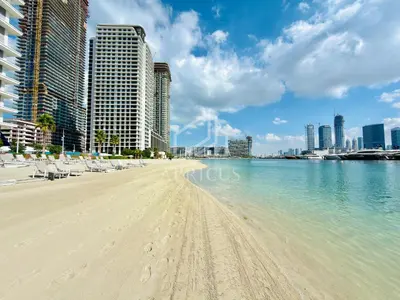 a beach with chairs and buildings in the water at Stunning 1 bedroom sea view apartment in Dubai