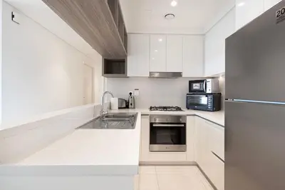 a white kitchen with a sink and a refrigerator at Stunning Burj Khalifa Views - Dubai Mall Access - Infinity Pool - MaxStays in Dubai