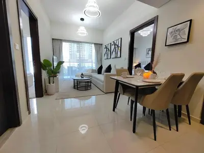 a dining room and living room with a table and chairs at Cozy 2BR Apartment DAMAC VERA Business Bay in Dubai