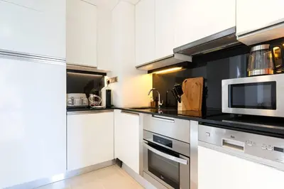 a kitchen with white cabinets and a microwave at The Magnificent in Dubai