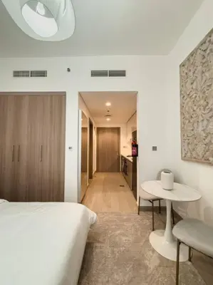 a bedroom with a white bed and a table at Newly Furnished Studio Azizi Riviera 37 Al Meydan in Dubai