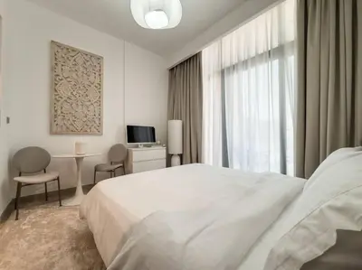a white bedroom with a bed and a table and a window at Newly Furnished Studio Azizi Riviera 37 Al Meydan in Dubai