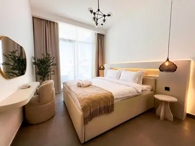 a bedroom with a large bed and a chair in it at 1-BR Gem with Luxe Amenities in JVC in Dubai