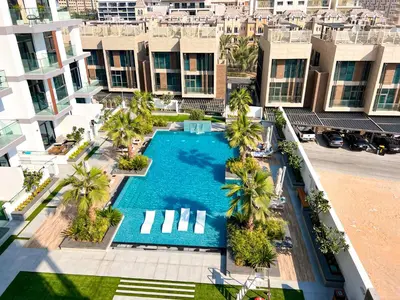 an overhead view of a swimming pool with palm trees and buildings at 1-BR Gem with Luxe Amenities in JVC in Dubai