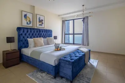 a blue bed with a blue tufted headboard in a bedroom at Frank Porter - Murjan 1 in Dubai
