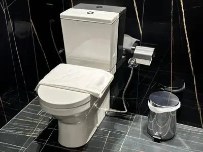 a white toilet in a bathroom with a trash can at Sleek & Spacious 1br Jvc Pool View in Dubai