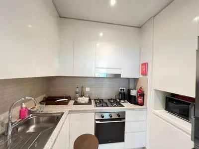 a kitchen with white cabinets and a sink and a stove at Downtown views-access to Dubai Mall! in Dubai
