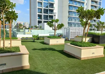 a park with palm trees and a large building at Fully Furnished One Bed in Meydan, Hosted by Desert City Stays in Dubai