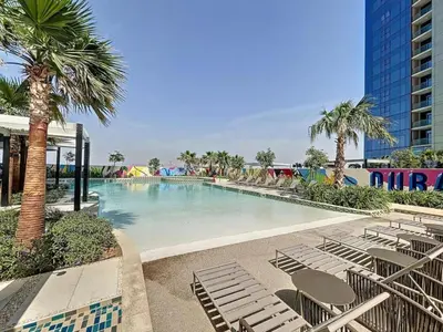 a large swimming pool with lounge chairs and palm trees at Samani vacation Homes 5701 in Dubai