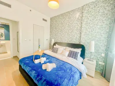 a bedroom with a large blue bed with two towels at Luxury 2 Bedroom in the Nook 1 next to Metro Energy in Dubai