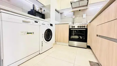 a white laundry room with a washer and dryer at Modern 1-Bedroom La Perla Apartment JVC with Infinity Pool & Kids’ Zone in Dubai