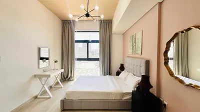 a bedroom with a bed and a mirror and a window at Modern 1-Bedroom La Perla Apartment JVC with Infinity Pool & Kids’ Zone in Dubai