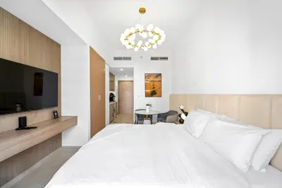 a bedroom with a large white bed and a chandelier at Studio Azizi Riviera 28 Community View in Dubai