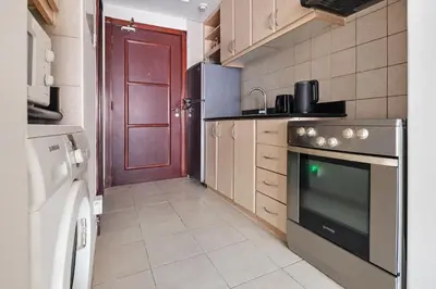 a kitchen with a stove and a red door at Urban Designer Apt - Family Friendly in Dubai