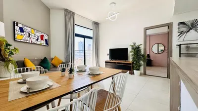 a dining room with a table and a living room at Premium 1-Bedroom Perla Apartment in JVC | Infinity Pool & Kids’ Play Area in Abu Dhabi
