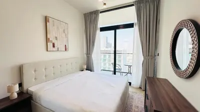 a bedroom with a white bed and a large window at Standard 1bedroom Apartment Binghatti Emerald JVC in Dubai
