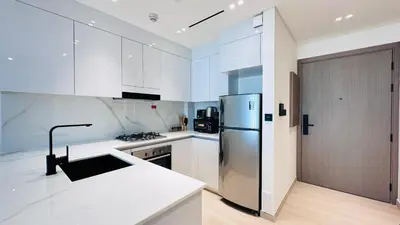 a kitchen with white cabinets and a stainless steel refrigerator at Standard 1bedroom Apartment Binghatti Emerald JVC in Dubai