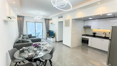 a kitchen and a living room with a table and a couch at Dubai Marina- Cozy 2BHK Apartment in Dubai