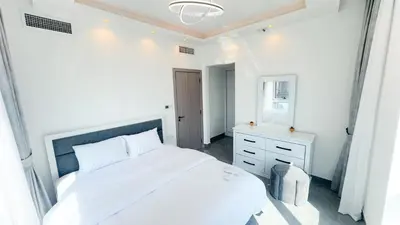 a white bedroom with a large white bed and a mirror at Dubai Marina- Cozy 2BHK Apartment in Dubai