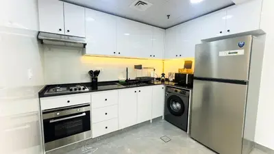 a kitchen with white cabinets and a stainless steel refrigerator at Dubai Marina- Cozy 2BHK Apartment in Dubai