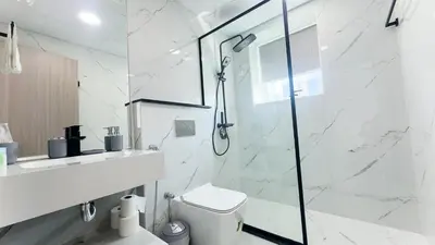 a white bathroom with a shower and a toilet at Dubai Marina- Cozy 2BHK Apartment in Dubai