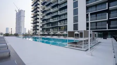 a large building with a swimming pool next to a building at Stylish 1br Jvc Spacious Layout Pool View in Dubai
